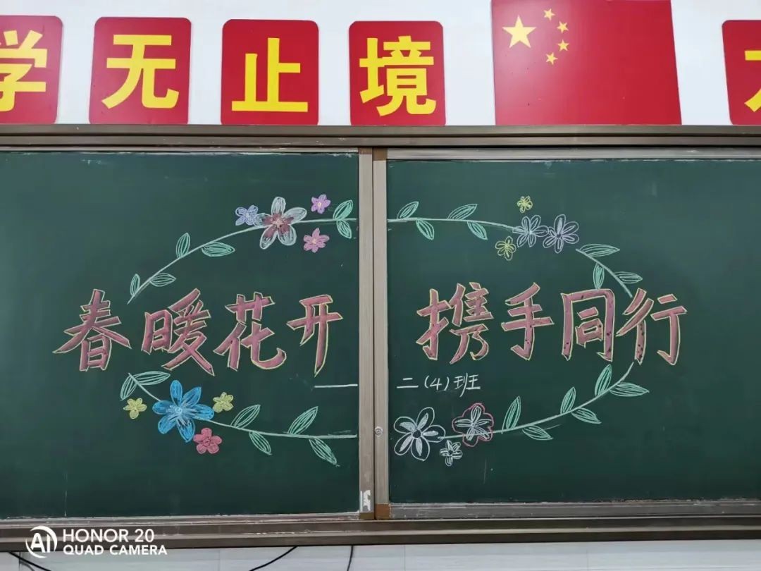班级老师提前在教室门口迎接家长,黑板上写着欢迎家长的标语及家长会
